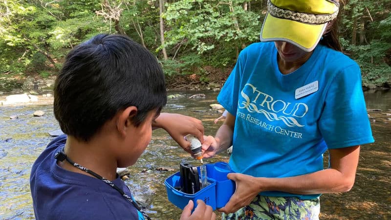 Tara Muenz and a child test pH in stream water.